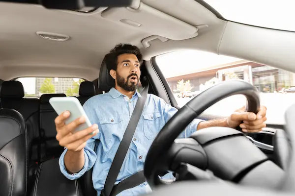 A distracted Uber or Lyft driver holding his phone moments before impact.