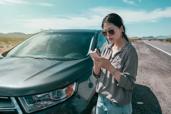 A woman calls someone while standing outside her car. An Alpharetta personal injury lawyer can help you navigate the complexities of the legal system in Georgia. 