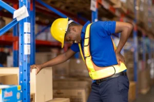 Injured warehouse worker holding lower back after lifting injury in Atlanta distribution center