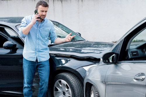 Man on a cell phone at the scene of a car accident