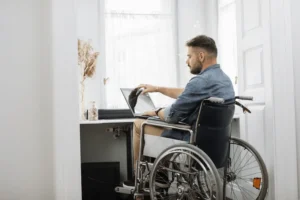 A worker in a wheelchair uses a laptop to review his TTD benefits.