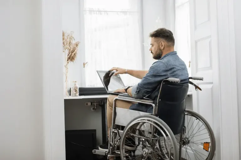 A worker in a wheelchair uses a laptop to review his TTD benefits.
