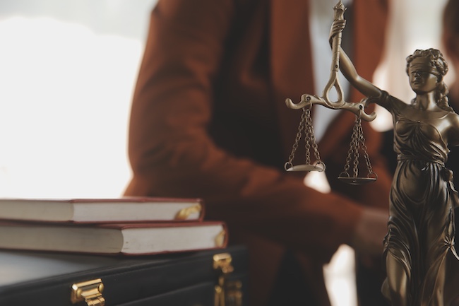 Statue of Lady Justice with scales beside legal books, representing legal support for car accident victims in Buford, Georgia.