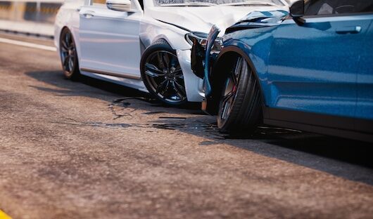 Car accident scene with a damaged white vehicle and a blue vehicle on a road, illustrating the consequences of distracted driving in Buford, Georgia.