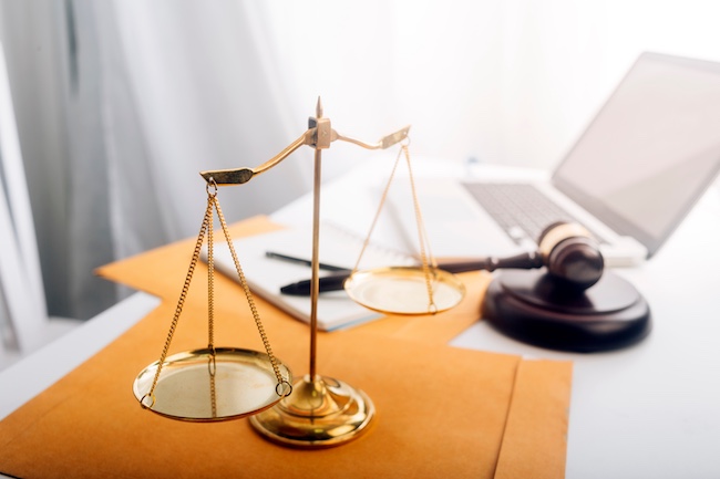 Gold balance scales symbolizing justice, lawyer's gavel, and legal documents on a desk, representing personal injury law and legal support for car accident victims in Buford, GA.