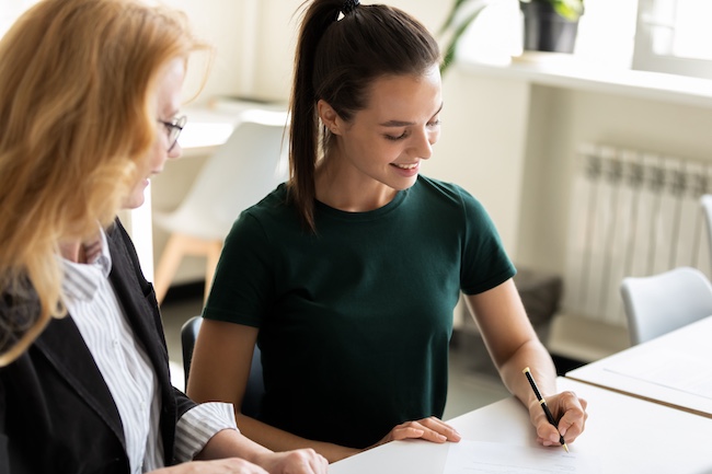 Woman signing documents with a Marietta car accident lawyer in a professional setting, emphasizing legal assistance and client support.
