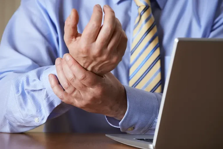 A businessman rubs his sore wrist, one of several types of repetitive strain injuries.