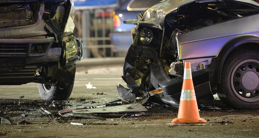 Car accident scene with two damaged vehicles, debris scattered, and a traffic cone indicating the site of a speeding crash in Buford, Georgia.