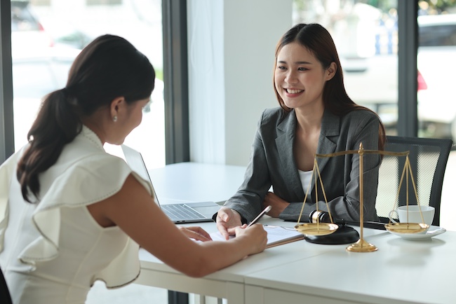 Lawyer consulting with client in office, discussing legal options for car accident cases, with scales of justice symbolizing legal representation.
