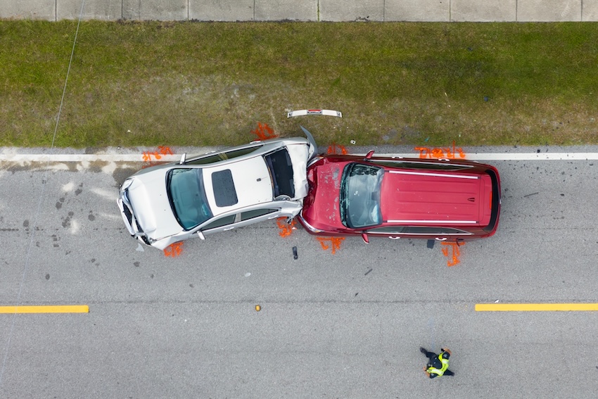 Aerial view of a car accident involving a silver SUV and a red vehicle on a roadway, with police officer assessing the scene, highlighting distracted driving risks in Buford, Georgia.