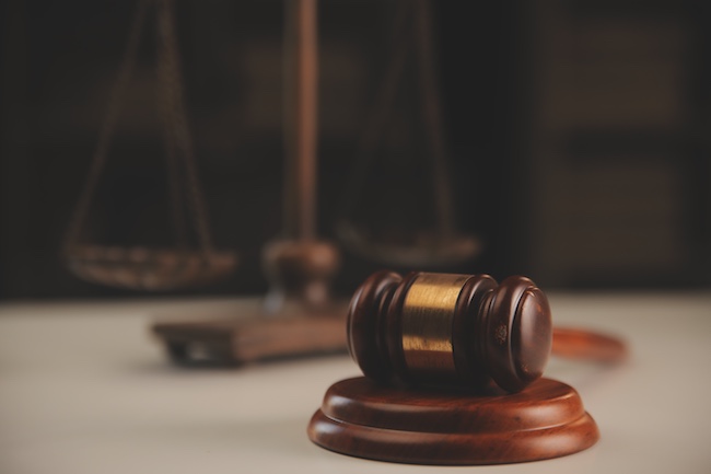 Gavel on a wooden block with a blurred background of a balance scale, symbolizing legal representation and personal injury law.
