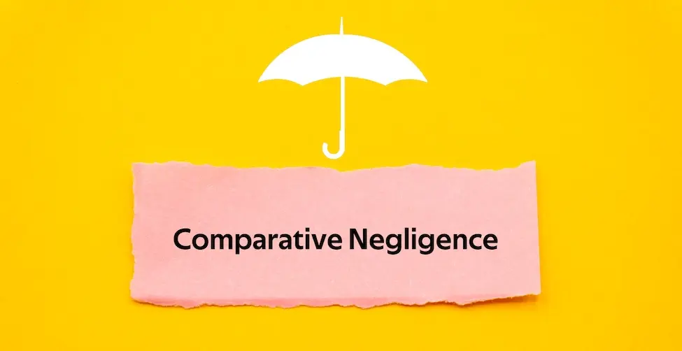 A white umbrella icon is above a pink torn paper slip that is displaying comparative negligence text on a bright yellow background representing the Law Offices of Humberto Izquierdo Jr. PC.