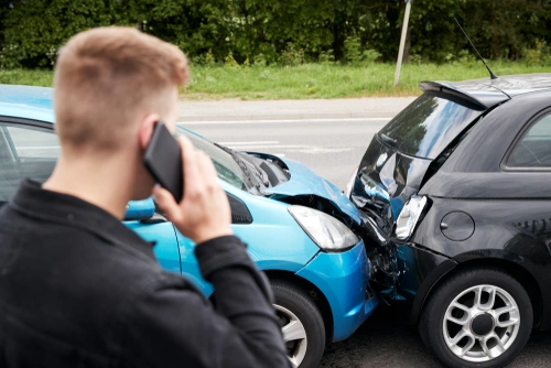 A man talking on the phone after a car accident whose injuries will appear later.