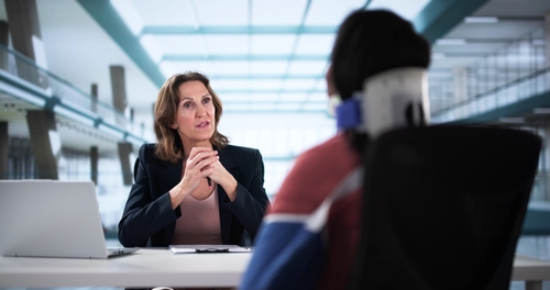 Workers' comp attorney discussing with a vicitm in a neck brace and arm cast about how a workers' compensation works in Georgia.