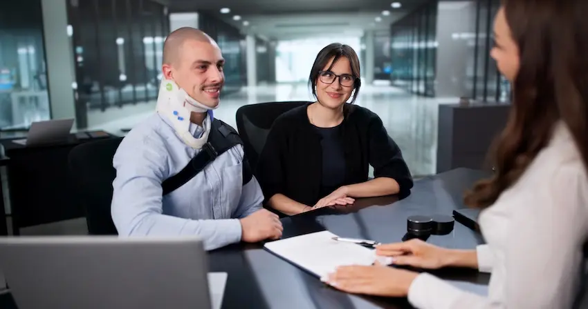 A friend and an injured client with a neck brace are meeting with an attorney to discuss a premises liability claim after a property accident at the Law Offices of Humberto Izquierdo Jr. PC in South Carolina.