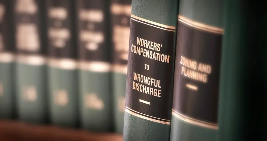 A row of green law books on a shelf with spines labeled Workers' Compensation to Wrongful Discharge representing the legal resources used to navigate workers' compensation leave claims and employment law at the Law Offices of Humberto Izquierdo, Jr. PC in Georgia.